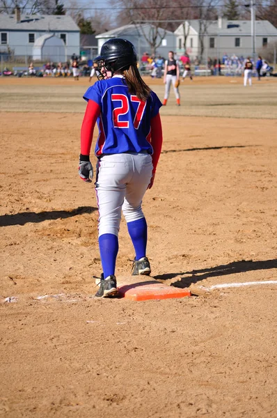 Teini tyttö softball pelaaja ensimmäinen pohja — kuvapankkivalokuva