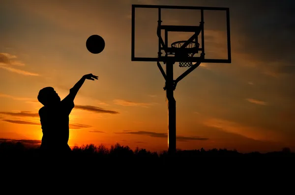 Silhouette von Teenie Boy & Basketball lizenzfreie Stockfotos