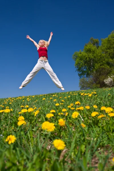 Genç kadın kırmızı kıyafeti çayır üzerinde eğleniyor — Stok fotoğraf