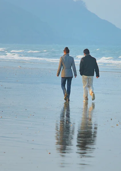 Una pareja caminando en una playa — Foto de Stock