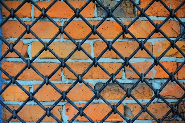 Шаблон из железной сетки и кирпичной стены — стоковое фото