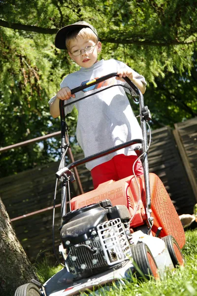 Мальчик стрижет траву в летний день — стоковое фото