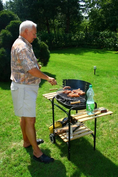 Old man outside cooking/ barbecuing — Stock Photo, Image