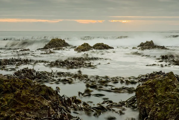 Pôr do sol sobre ondas e rochas — Fotografia de Stock