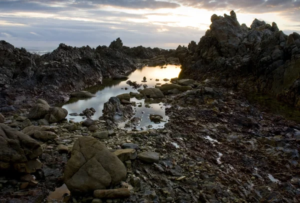 Günbatımı üzerinde kayalık plaj — Stok fotoğraf