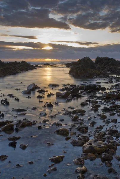 Günbatımı kayalık su üzerinde — Stok fotoğraf