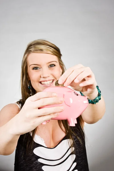 Woman putting money in piggy bank — Stock Photo, Image
