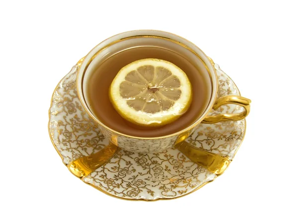 Gold porcelain cup with tea and lemon — Stock Photo, Image