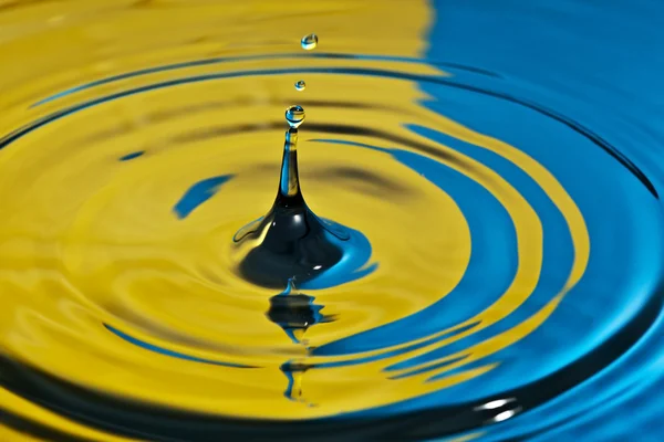 Water splash in geel en blauw — Stockfoto
