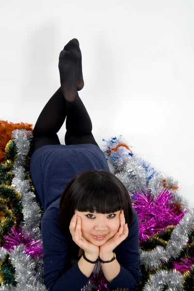 Mooi meisje liggen onder klatergoud — Stockfoto