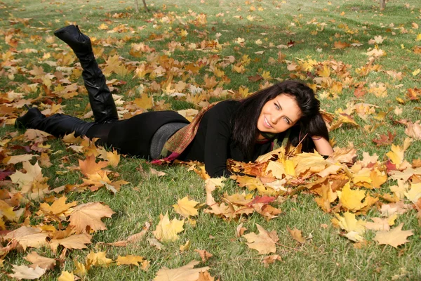 Smiling woman lying on a carpet of leave — Stock Photo, Image