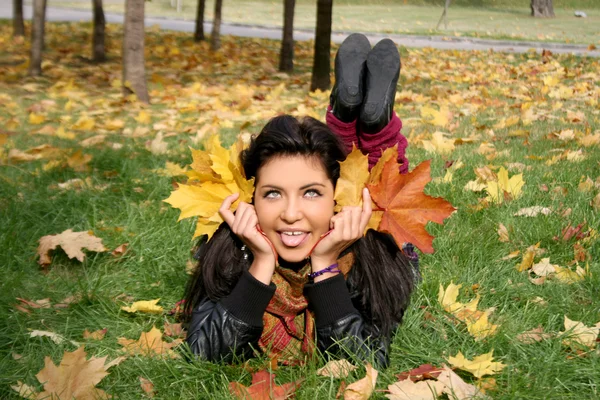 Mujer divertida acostada en una alfombra de hojas —  Fotos de Stock