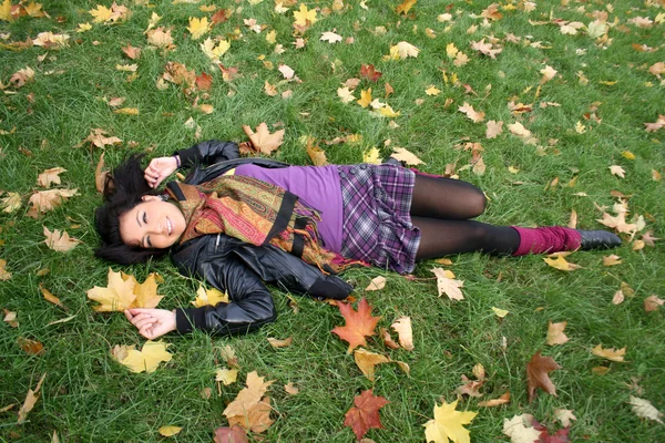 Mutlu bir kadın yaprakları bir halı üzerinde yalan — Stok fotoğraf