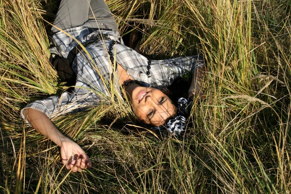 Vacker ung kvinna liggande på fältet — Stockfoto