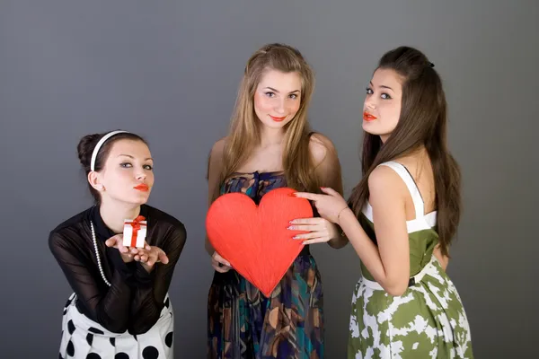 Три щасливі дівчата тримають червоне серце — стокове фото