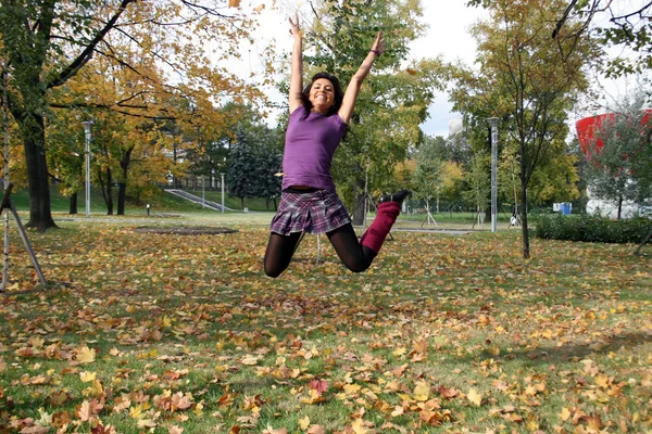 Donna gioiosa che salta nel parco autunnale — Foto Stock
