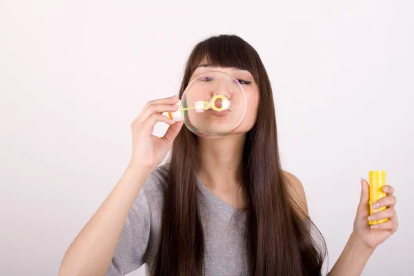Girl blowing soap bubbles in studio — Stock Photo, Image