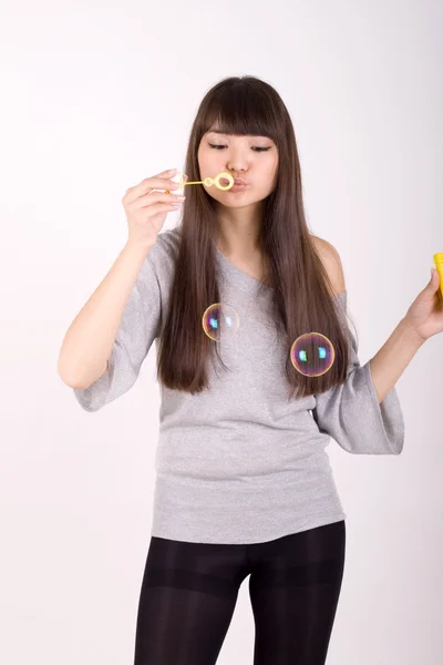 Chica soplando burbujas de jabón en el estudio —  Fotos de Stock