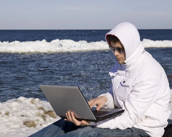 Young man with the computer on seacoats — Stock Photo, Image