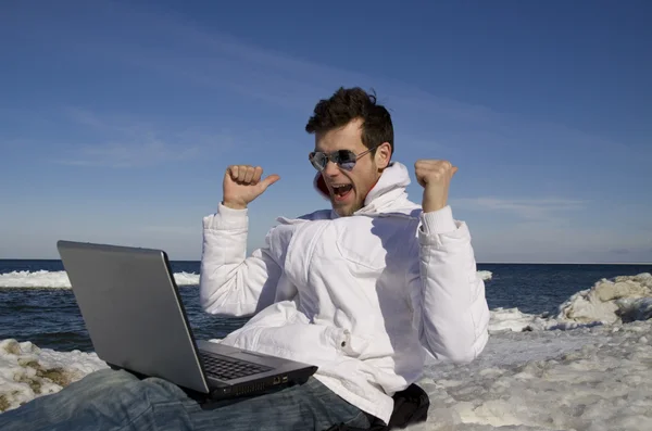 Young man with the computer on seacoats — Stock Photo, Image