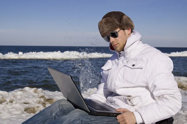 stock image Young man with the computer on seacoats