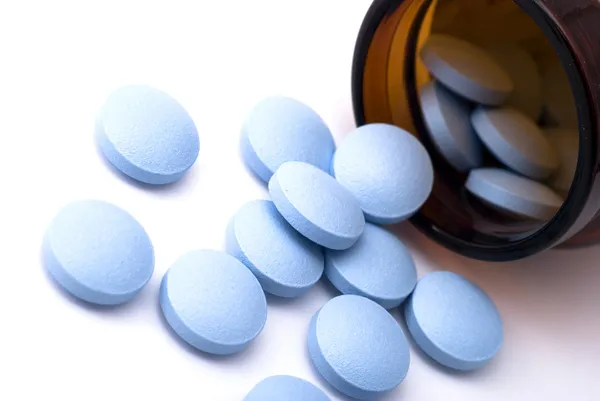 Bouteille brune avec des pilules bleues dispersées — Photo