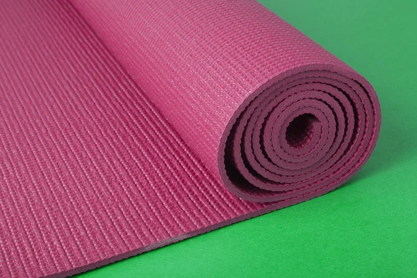 Розовый коврик для йоги на зеленом — стоковое фото