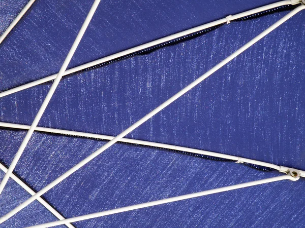 Raggi bianchi su ombrellone blu — Foto Stock