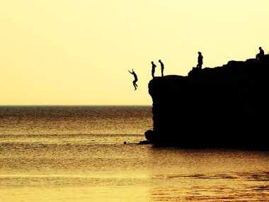 Jumping of a cliff at sunset