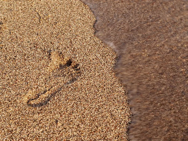 Wave radera fotspår i sand — Stockfoto