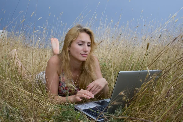 Girl in a field with laptop — Stok Foto