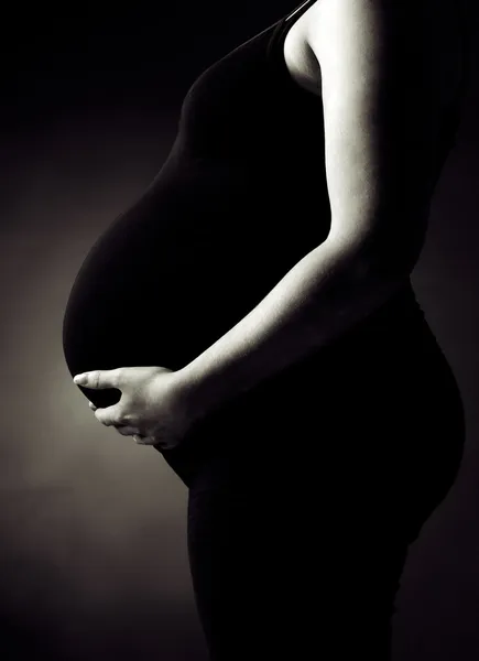 Zwangere vrouw ter ondersteuning van haar buik — Stockfoto