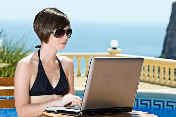 Tyttö bikinit käyttäen hänen kannettava tietokone — kuvapankkivalokuva