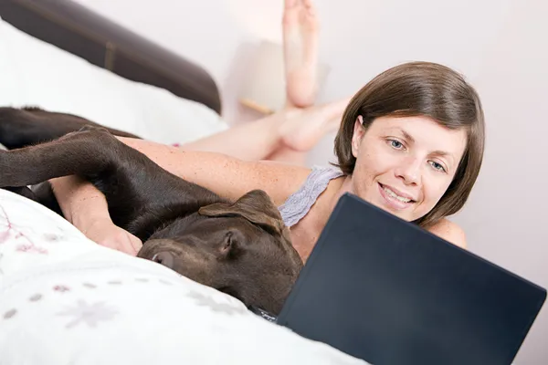 Dame kuschelt Labrador auf Bett — Stockfoto