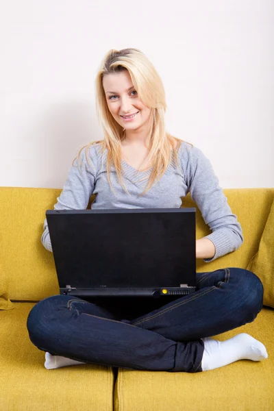 Woman with computer sitting on couch — Stock Photo, Image