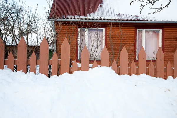 Cerca de madeira e casa no inverno Imagens Royalty-Free