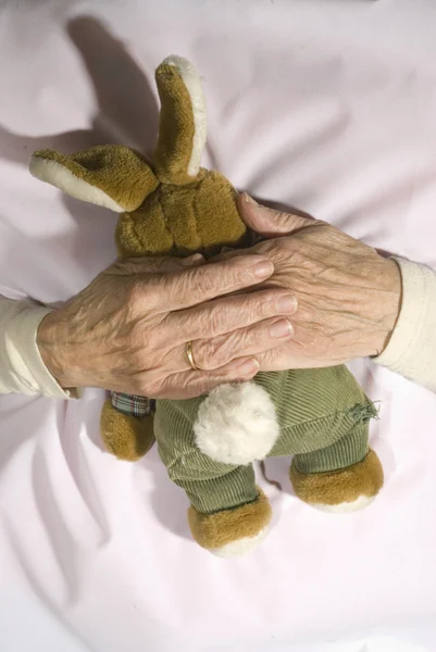 Old demented person with stuffed rabbit — Stock Photo, Image
