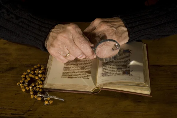 Oude handen met de Bijbel en rozenkrans — Stockfoto