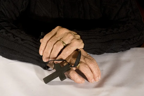 Mãos velhas com cruz preta — Fotografia de Stock