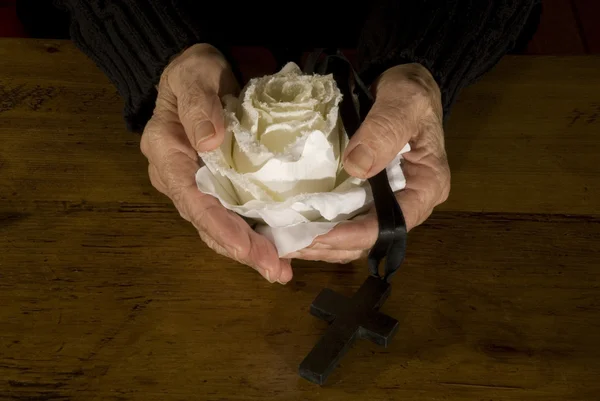 Old hands with white rose and cross — Stock Photo, Image