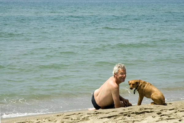 Человек с собакой на пляже — стоковое фото