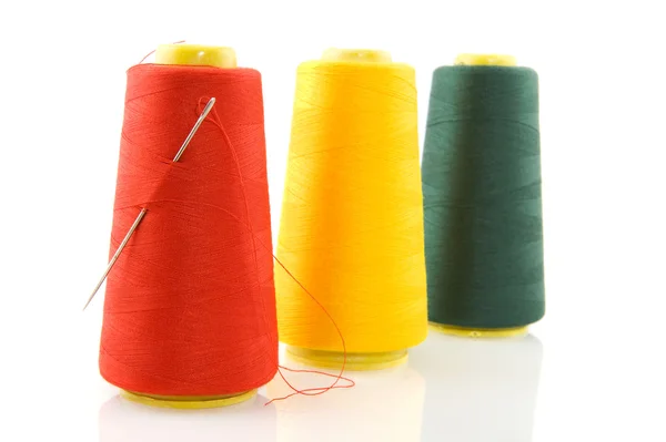 Three bobbins with threads and needle — Stock Photo, Image