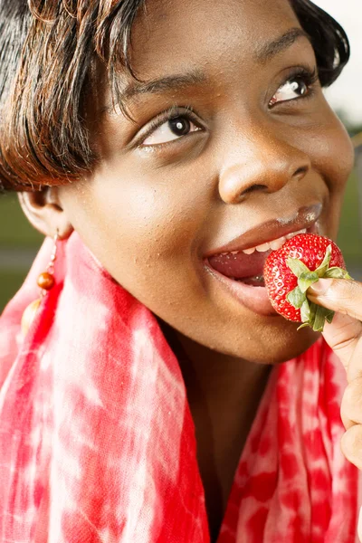 Mulher com cachecol vermelho comendo um morango — Fotografia de Stock