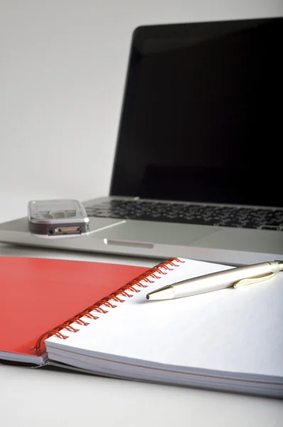 Telefon, laptop og tom notesbog på skrivebordet - Stock-foto
