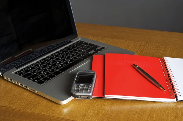 Telefon, laptop og tom notesbog på skrivebordet - Stock-foto