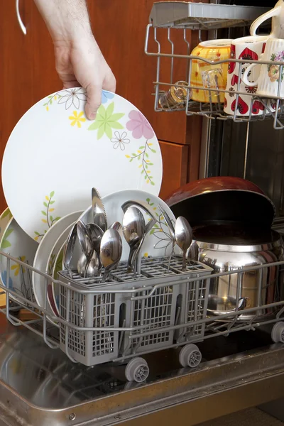 Вытаскивание тарелки из посудомоечной машины — стоковое фото