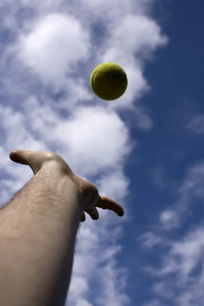 Рука людини кидаючи тенісний м'яч — стокове фото