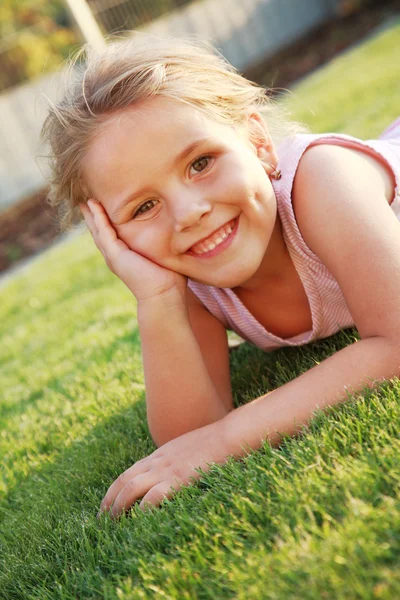 Gelukkig meisje ontspannen op een gras — Stockfoto