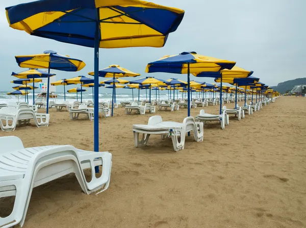 Guarda-chuvas e cadeiras de sol em uma praia — Fotografia de Stock