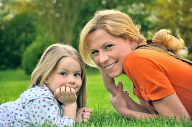 Young mother and daughter laying clipart